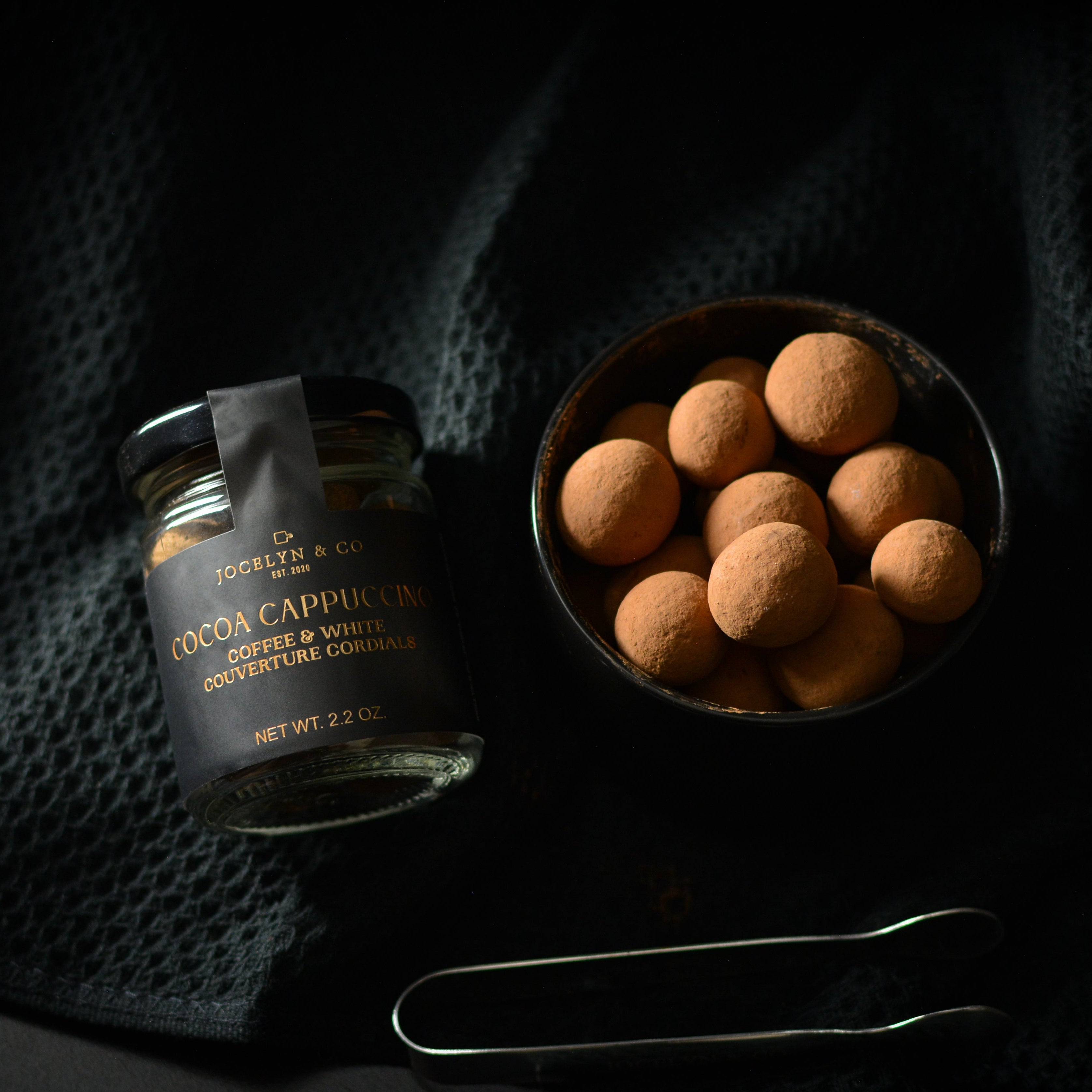 Jar of cocoa truffles on a dark fabric background