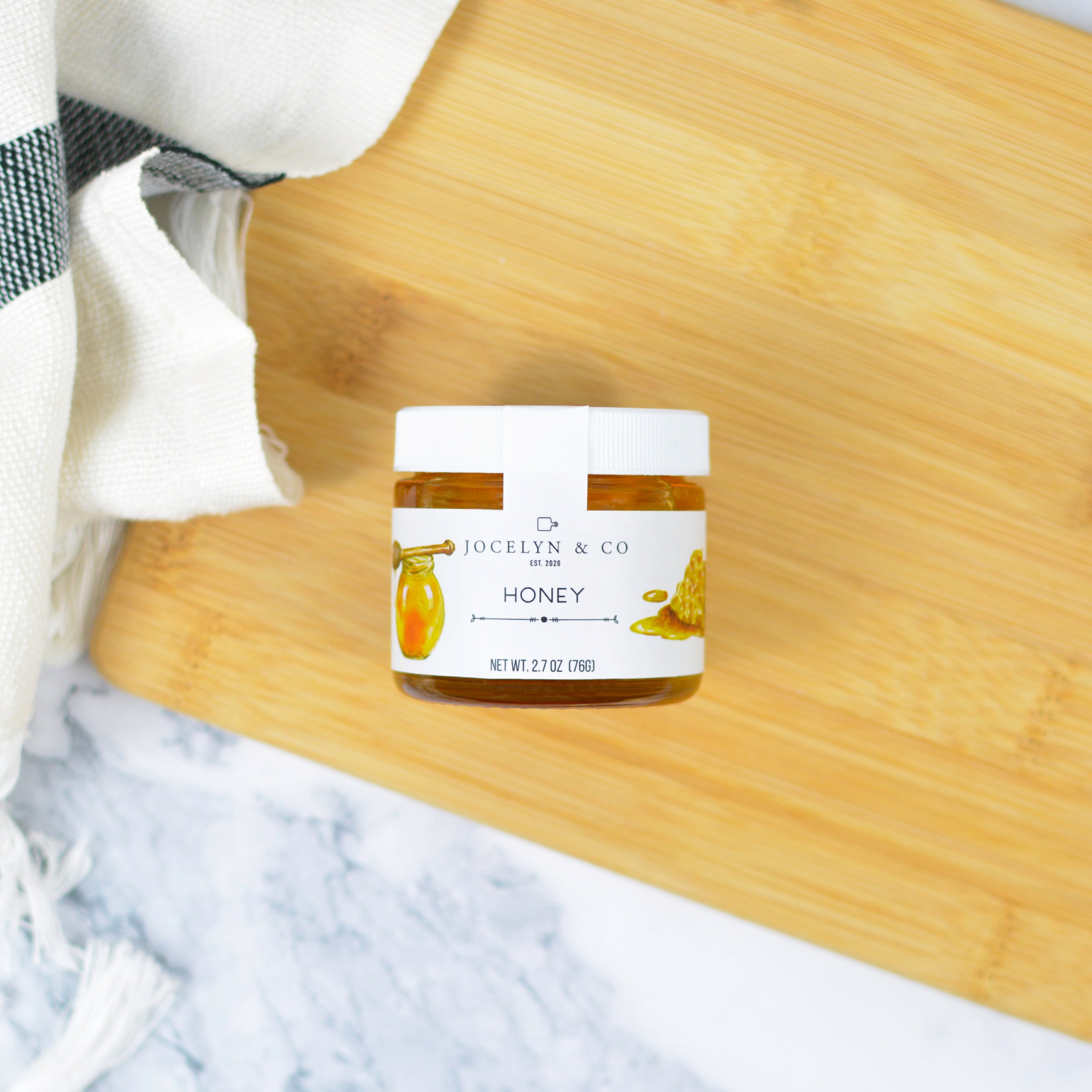 Jar of honey on a ooden cutting board ith a marble background